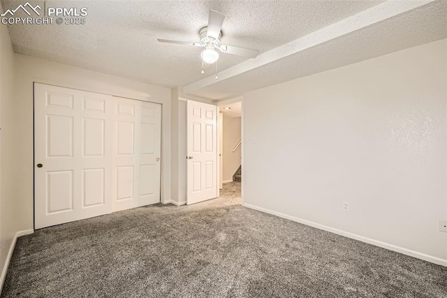 unfurnished bedroom featuring carpet, a ceiling fan, a closet, a textured ceiling, and baseboards