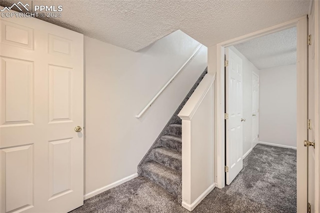 stairway featuring carpet, a textured ceiling, and baseboards