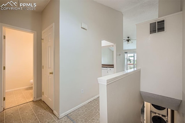 hall featuring visible vents, an upstairs landing, and baseboards