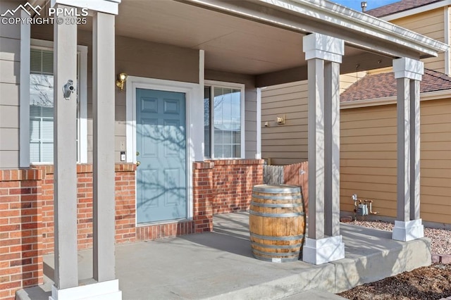 entrance to property with covered porch and brick siding