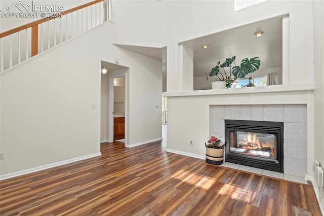 unfurnished living room featuring baseboards, visible vents, wood finished floors, and a fireplace
