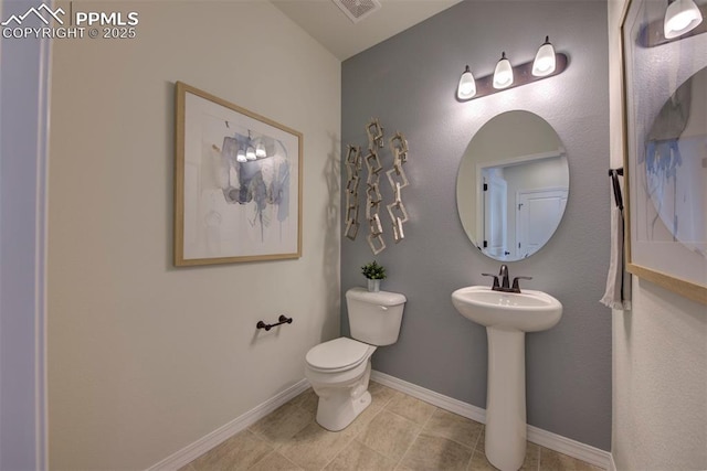 half bath featuring visible vents, tile patterned flooring, a sink, baseboards, and toilet
