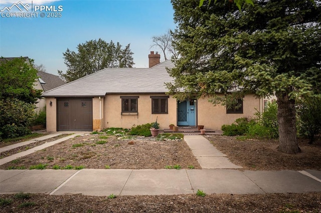 2126 Wood Ave, Colorado Springs, CO 80907 - view of front of home with stucco siding, an attached garage, a chimney, and driveway