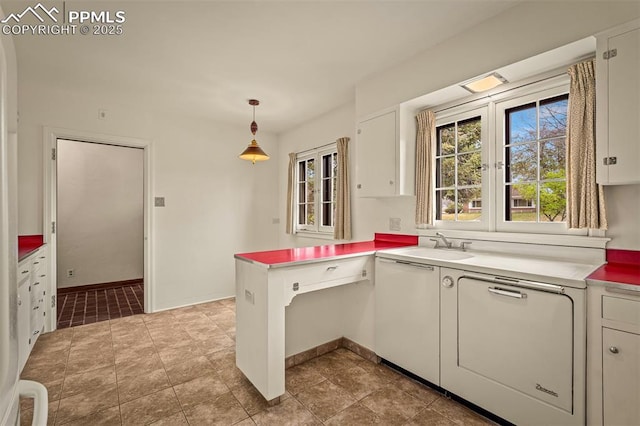 2126 Wood Ave, Colorado Springs, CO 80907 - kitchen featuring white cabinets, a peninsula, light countertops, hanging light fixtures, and a sink