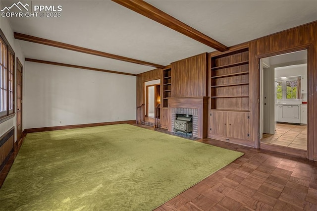2126 Wood Ave, Colorado Springs, CO 80907 - unfurnished living room with beamed ceiling, baseboards, wood walls, and a fireplace