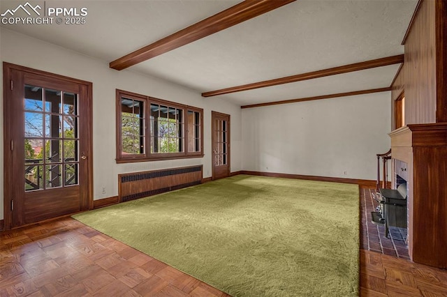 2126 Wood Ave, Colorado Springs, CO 80907 - unfurnished living room featuring radiator heating unit, beam ceiling, baseboards, and a fireplace with flush hearth
