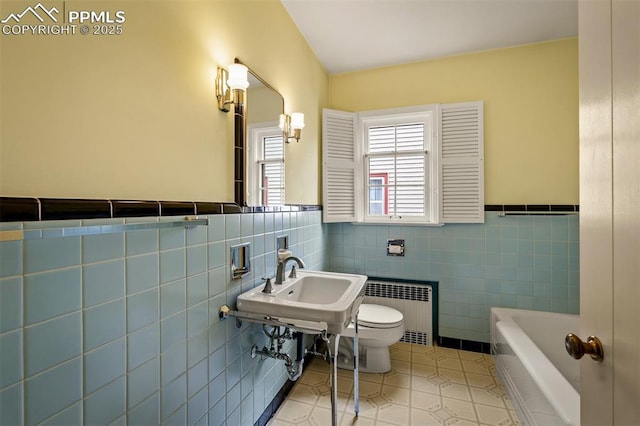 2126 Wood Ave, Colorado Springs, CO 80907 - bathroom with radiator, tile walls, tile patterned floors, toilet, and wainscoting