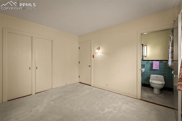 2126 Wood Ave, Colorado Springs, CO 80907 - unfurnished bedroom with carpet flooring, ensuite bath, tile walls, and a closet