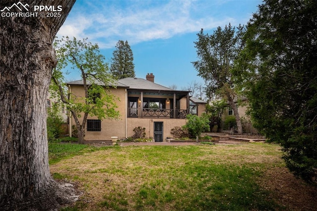 2126 Wood Ave, Colorado Springs, CO 80907 - back of house featuring stucco siding, a yard, and a chimney