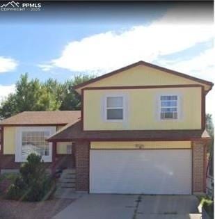 3425 Post Oak Dr, Colorado Springs, CO 80916 - view of front of home with an attached garage, concrete driveway, and brick siding