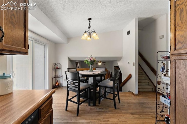 3425 Post Oak Dr, Colorado Springs, CO 80916 - dining space featuring a chandelier, light wood-type flooring, stairs, and a textured ceiling