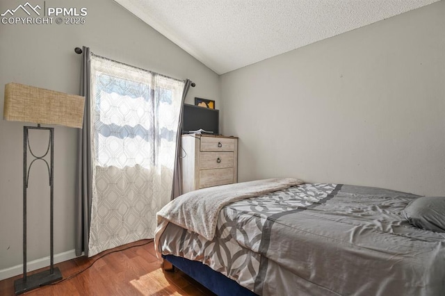 bedroom featuring wood finished floors, a textured ceiling, and vaulted ceiling