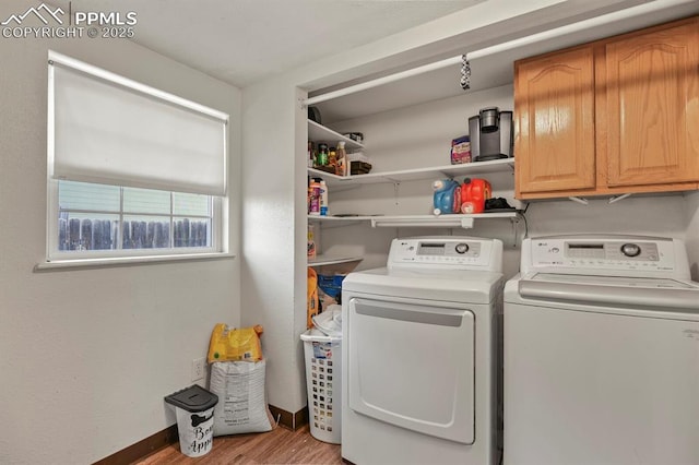 laundry room featuring baseboards, washer and clothes dryer, cabinet space, and wood finished floors