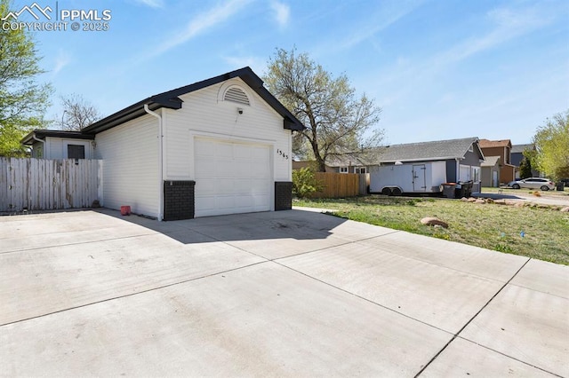 view of side of property with brick siding, driveway, fence, and a lawn