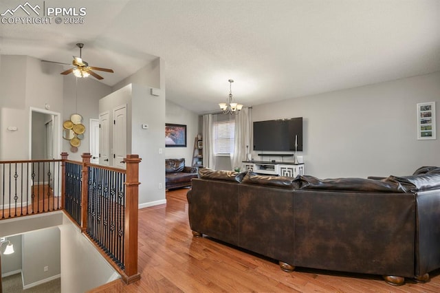 living room featuring baseboards, wood finished floors, ceiling fan with notable chandelier, and vaulted ceiling