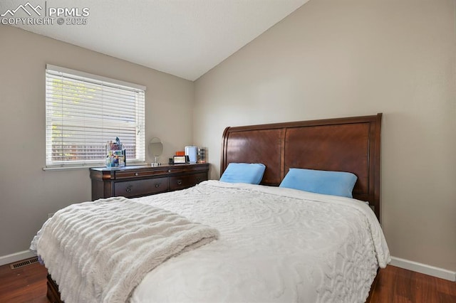 bedroom with dark wood-style flooring, baseboards, and lofted ceiling