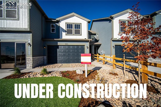 view of front of home with fence, a garage, stone siding, and board and batten siding