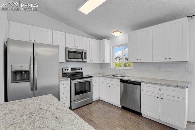 7920 Conifer Dr, Colorado Springs, CO 80920 - kitchen featuring appliances with stainless steel finishes, a sink, vaulted ceiling, dark wood finished floors, and decorative backsplash