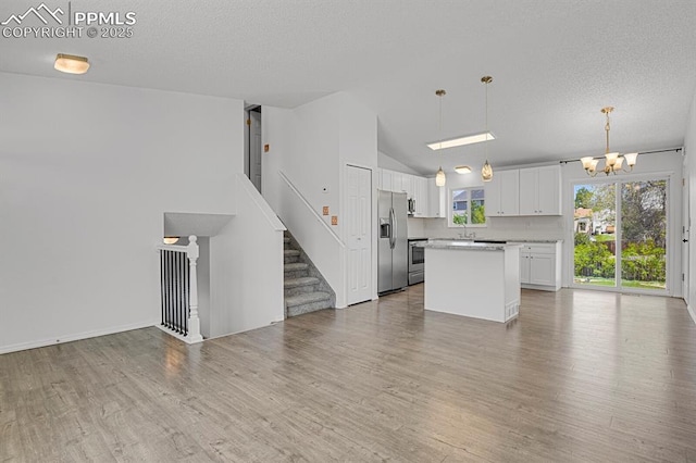 7920 Conifer Dr, Colorado Springs, CO 80920 - kitchen with stainless steel fridge, open floor plan, a chandelier, a center island, and white cabinetry