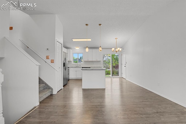 7920 Conifer Dr, Colorado Springs, CO 80920 - kitchen with a chandelier, stainless steel fridge, white cabinetry, wood finished floors, and a center island