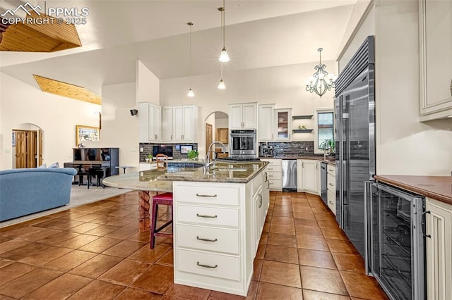 17995 Minglewood Trl, Monument, CO 80132 - kitchen featuring wine cooler, backsplash, arched walkways, a kitchen breakfast bar, and high vaulted ceiling