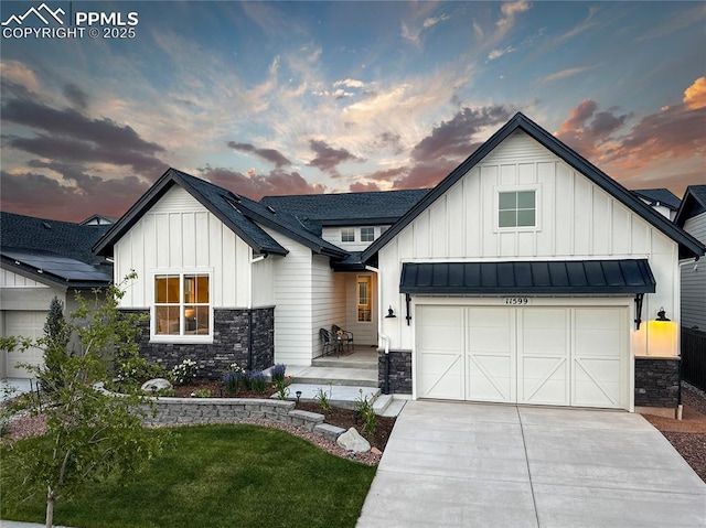 modern farmhouse style home featuring board and batten siding, stone siding, driveway, and an attached garage