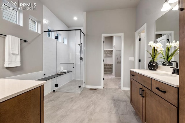 full bathroom with a stall shower, a walk in closet, and vanity