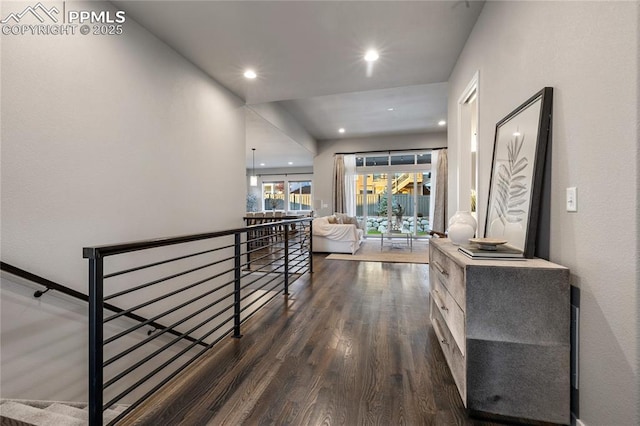 hall featuring an upstairs landing, dark wood-style floors, and recessed lighting