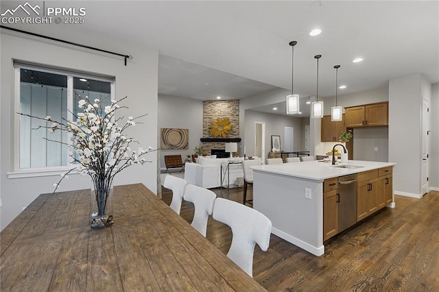 kitchen with dishwasher, dark wood-style flooring, a sink, brown cabinets, and recessed lighting