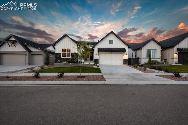 modern inspired farmhouse with board and batten siding, an attached garage, driveway, stone siding, and a front lawn