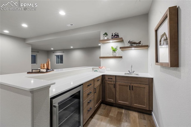 indoor wet bar with beverage cooler, wood finished floors, and recessed lighting