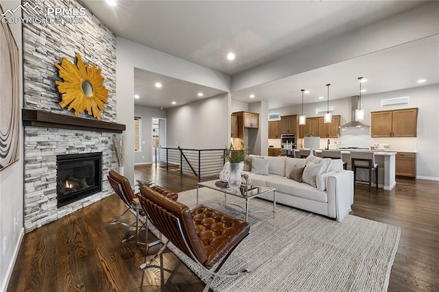 living area with dark wood-style floors, baseboards, recessed lighting, and a fireplace