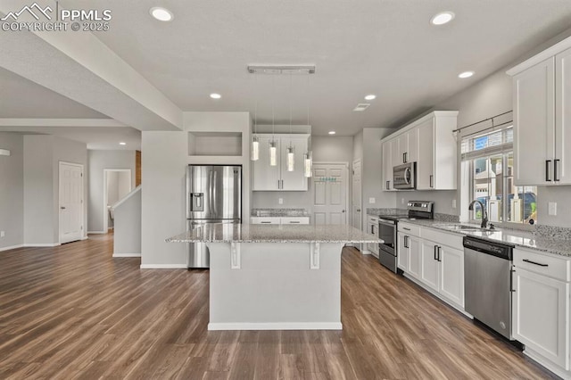 7238 Fauna Glen Dr, Colorado Springs, CO 80927 - kitchen featuring appliances with stainless steel finishes, a center island, white cabinetry, a kitchen breakfast bar, and recessed lighting