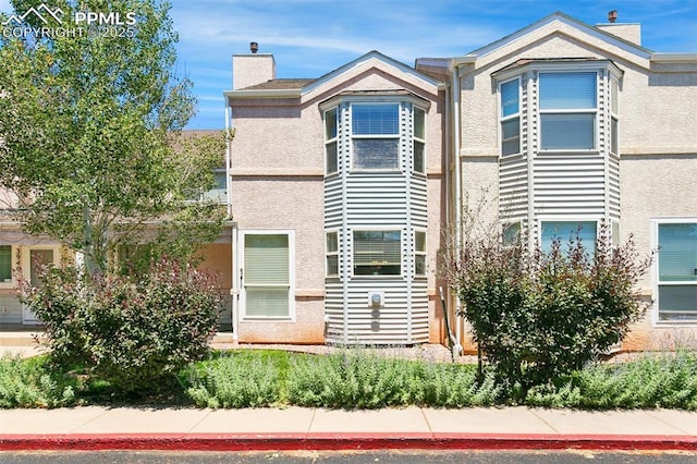 view of front of home featuring a chimney and stucco siding