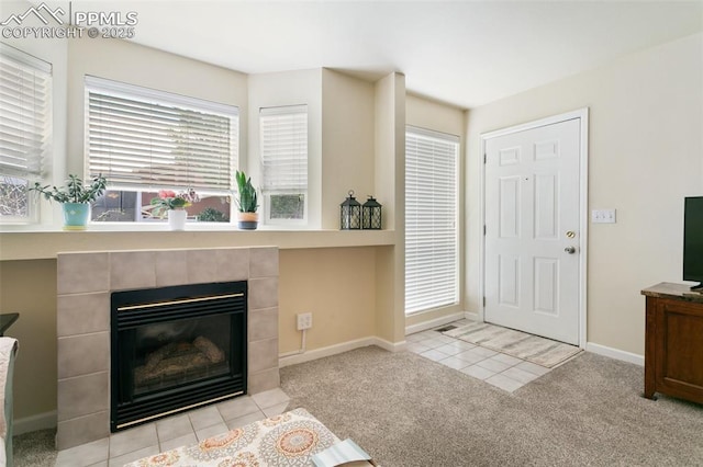 carpeted foyer entrance featuring baseboards, a tiled fireplace, and tile patterned flooring