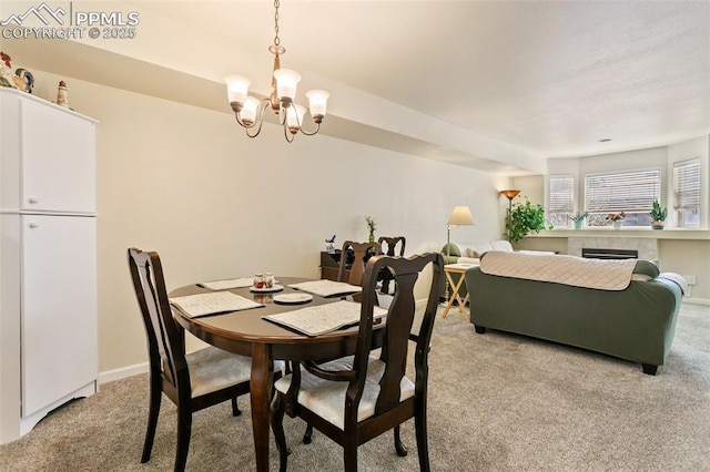 dining room with light colored carpet, a chandelier, and a fireplace