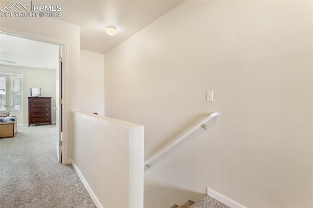 hallway with an upstairs landing, carpet flooring, and baseboards