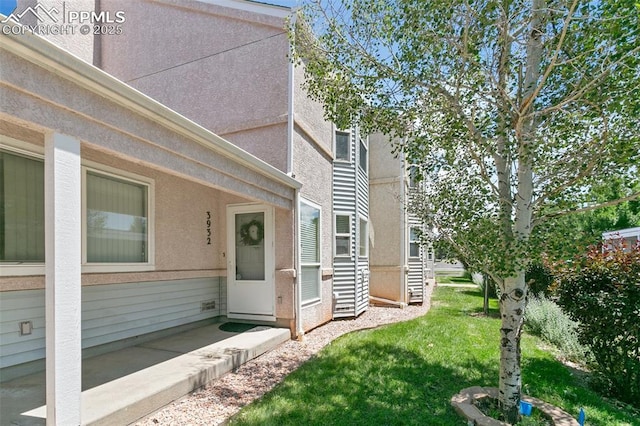 view of side of home featuring a lawn and stucco siding