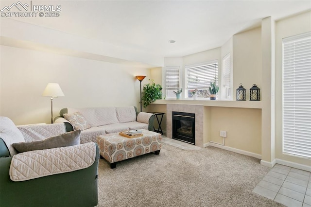 tiled living room with a tile fireplace, carpet, and baseboards