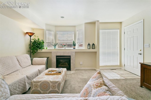 carpeted living room with a tile fireplace and baseboards