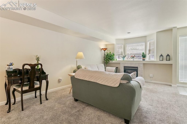 living area with carpet floors, baseboards, and a tiled fireplace