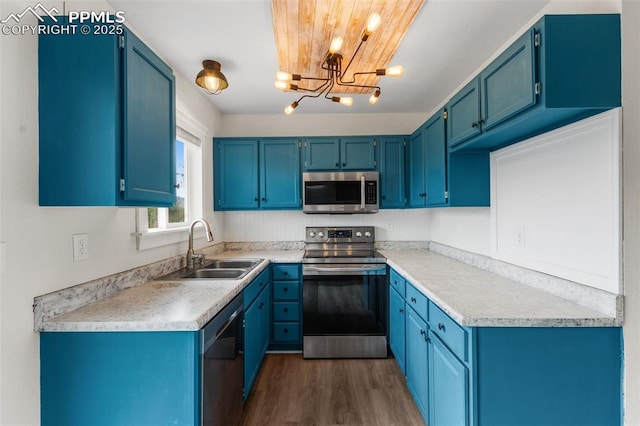 4650 Cassidy St, Colorado Springs, CO 80911 - kitchen featuring a notable chandelier, blue cabinets, a sink, appliances with stainless steel finishes, and dark wood-style floors