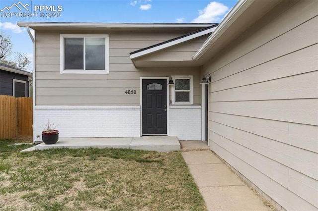 4650 Cassidy St, Colorado Springs, CO 80911 - view of exterior entry featuring a yard, fence, and brick siding
