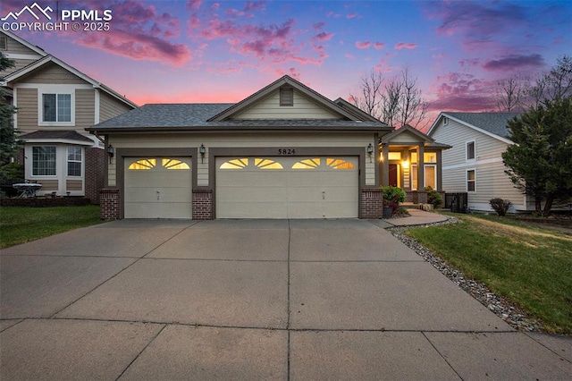 traditional home with brick siding, a garage, concrete driveway, a lawn, and roof with shingles