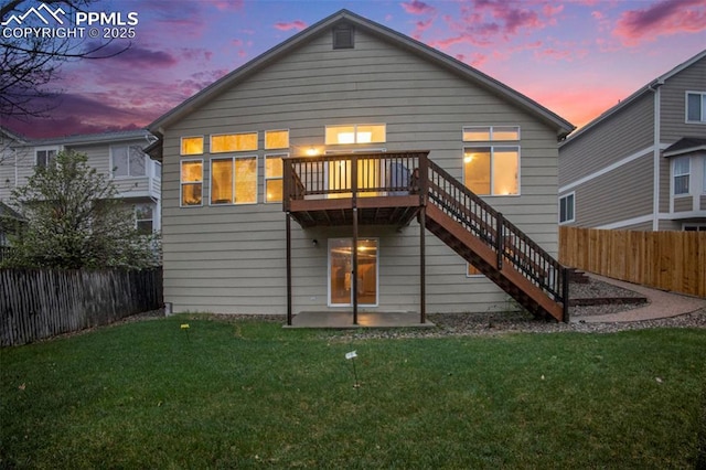 back of house at dusk featuring stairway, a wooden deck, and a patio