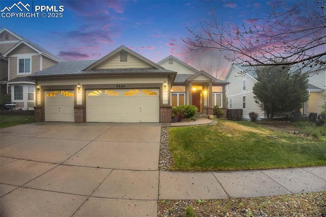 view of front facade with brick siding, an attached garage, a lawn, and driveway
