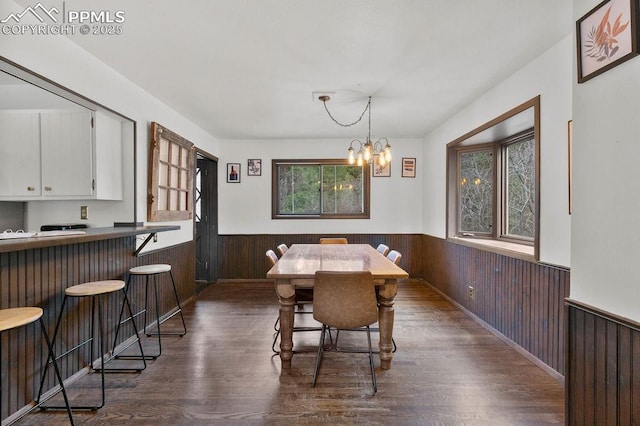 9410 Shoshone Rd, Cascade, CO 80809 - dining space with a wainscoted wall, wood walls, dark wood-style flooring, and a chandelier