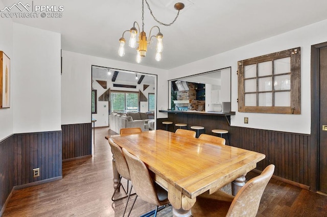 9410 Shoshone Rd, Cascade, CO 80809 - dining space with wainscoting, wooden walls, wood finished floors, and a chandelier