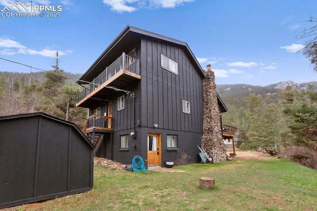9410 Shoshone Rd, Cascade, CO 80809 - rear view of property featuring a balcony, a storage shed, board and batten siding, and a yard