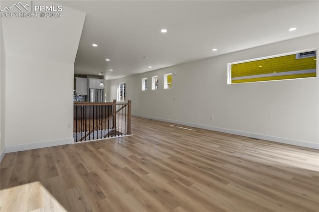 unfurnished living room featuring recessed lighting, baseboards, and light wood-style flooring
